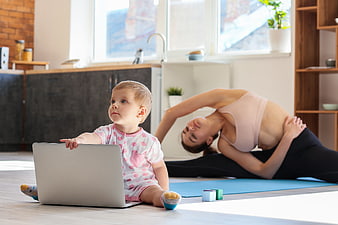 Mother doing yoga while baby plays with laptop at home