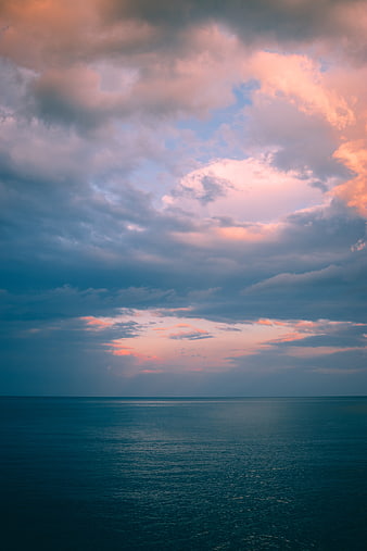 Dramatic Sunset Over Calm Ocean With Pink And Blue Clouds