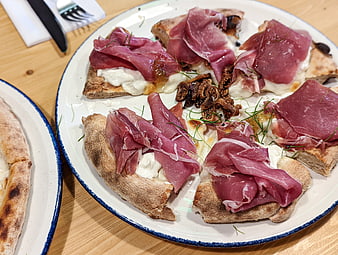 Gourmet pizza slices with prosciutto, burrata, and figs