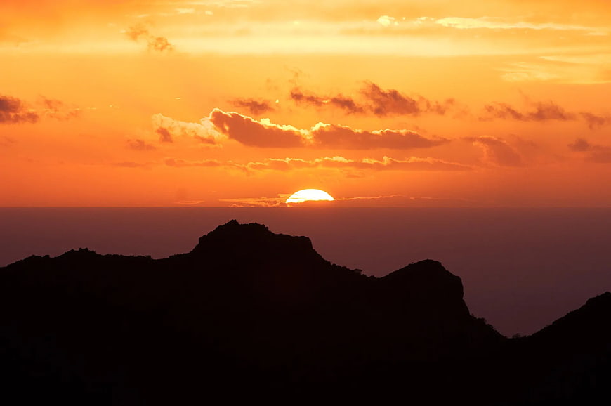 Silhouette of Mountain Ridge Against Vibrant Orange Sunset Sky