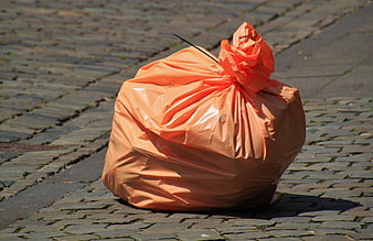 Orange plastic trash bag on cobblestone street