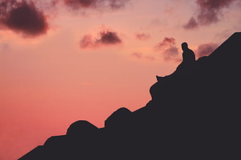 Silhouette of Man Sitting on Mountain Peak at Sunset