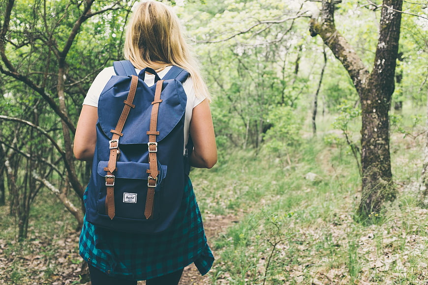 Young Woman Hiking in Forest with Blue Backpack