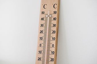 Wooden Thermometer on White Wall Showing High Temperature
