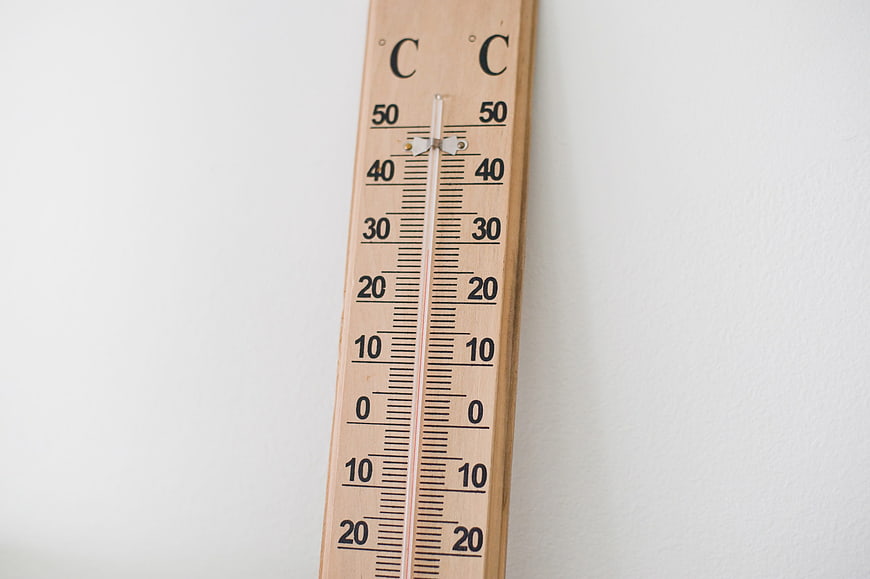 Wooden Thermometer on White Wall Showing High Temperature