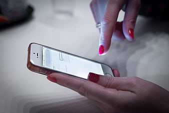 Close-up of woman's hands using smartphone with red nails
