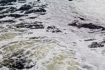 Polluted River Water Surface With Dark Sewage Foam And Bubbles