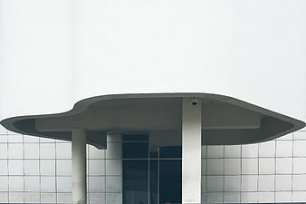 Modern white building entrance with curved concrete canopy