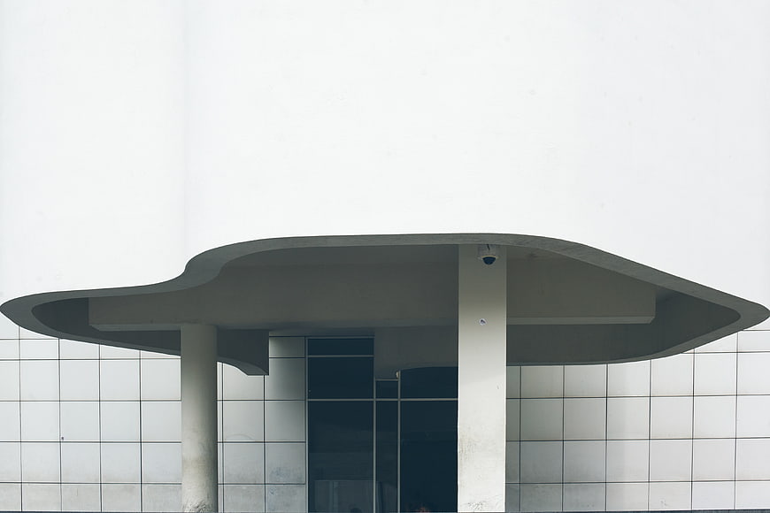 Modern white building entrance with curved concrete canopy