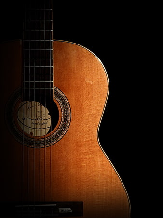 Close-up of acoustic guitar body on black background