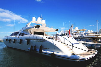 White luxury yacht docked in marina under blue sky