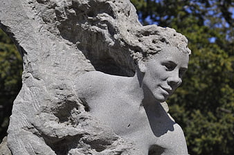 Close-up of weathered stone sculpture face in sunlight