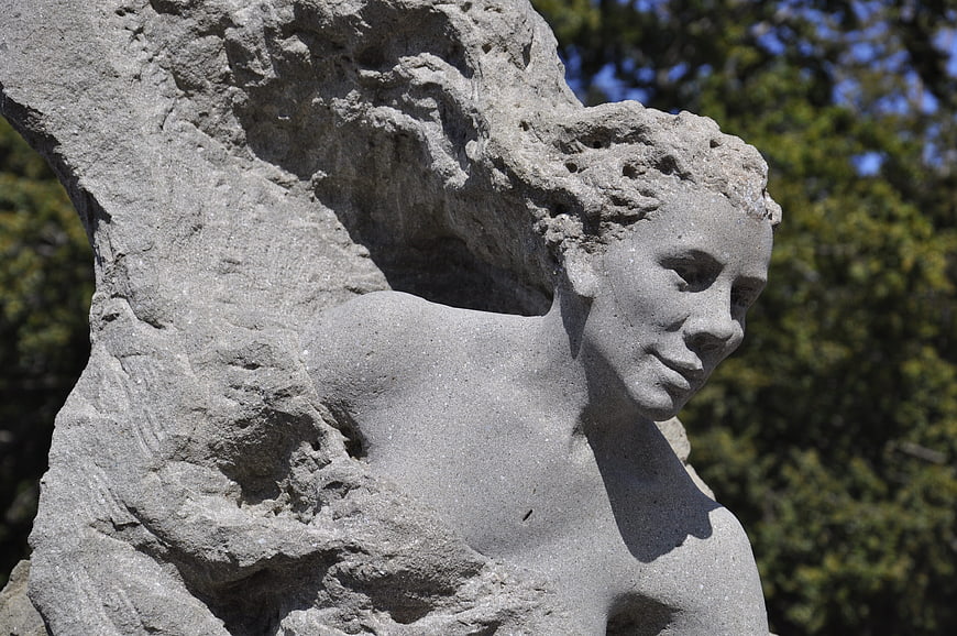 Close-up of weathered stone sculpture face in sunlight
