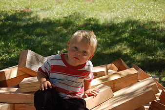 Toddler boy playing with wooden blocks outdoors