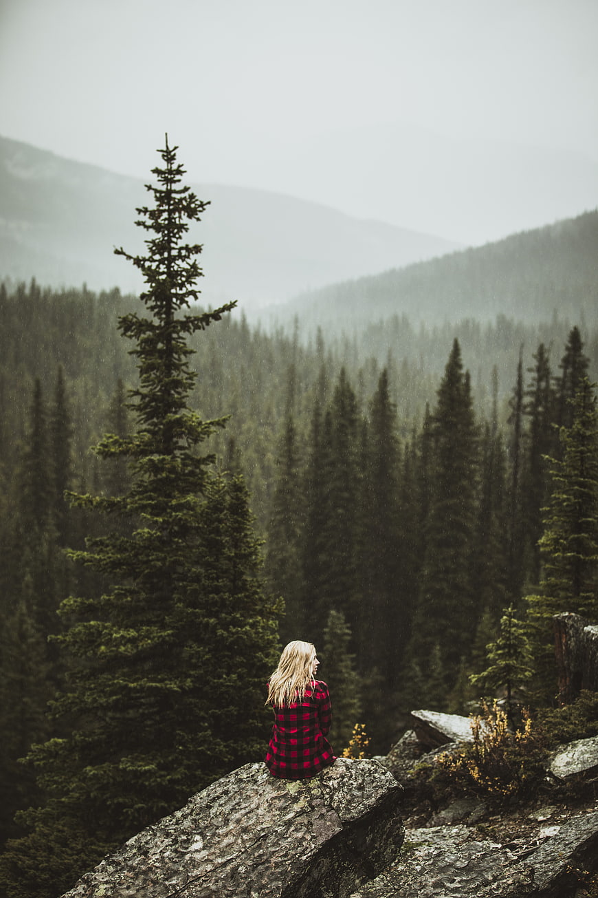 Woman in Red Plaid Sitting on Cliff Overlooking Misty Forest
