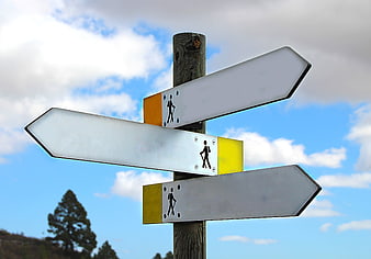 Hiking Trail Signpost With Directional Arrows Against Blue Sky