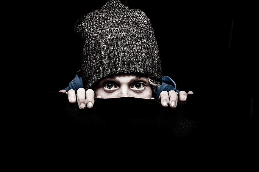 Child Peeking Over Black Barrier Wearing Knit Beanie