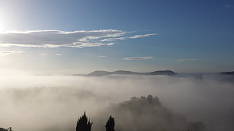 Misty mountain landscape with sea of clouds and blue sky