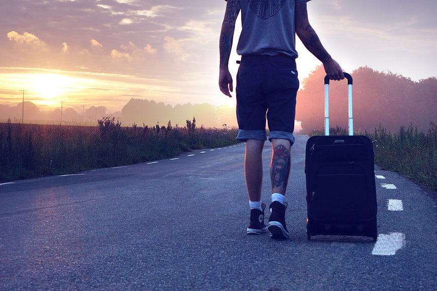 Man Walking Down Road with Suitcase at Sunset