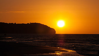 Golden sunset over the ocean with silhouetted coastal headland