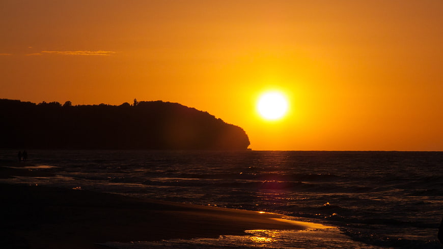 Golden sunset over the ocean with silhouetted coastal headland