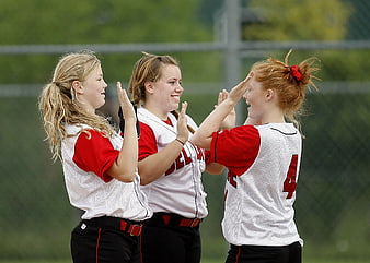 Three female softball players celebrating high five