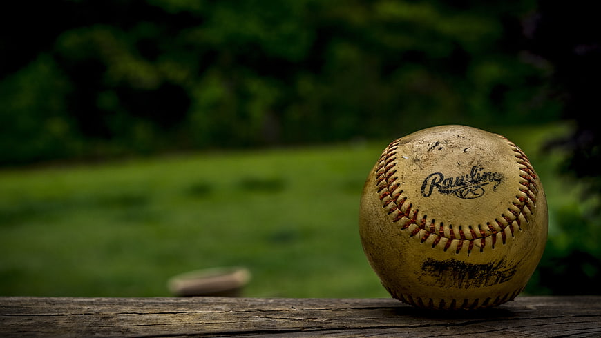 Close-up of a worn baseball on a wooden fence