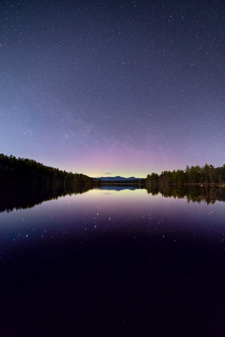 Starry Night Sky Reflection on Calm Lake with Forest Silhouette