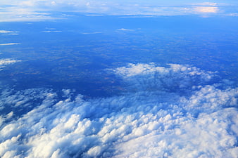 Aerial view of fluffy white clouds over blue landscape