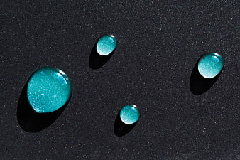 Shimmering teal liquid drops on dark textured background
