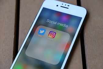 White Smartphone Displaying Social Media Apps On Wooden Surface
