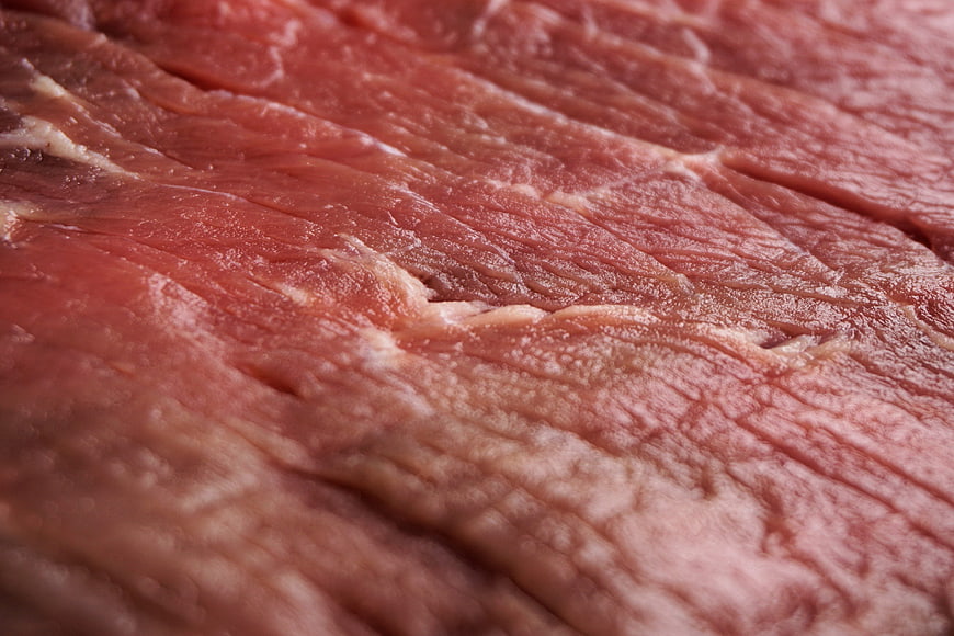 Close-up of raw red meat texture with visible grain and marbling