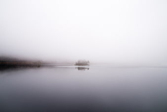 Misty Lake with Small Island and Foggy Horizon