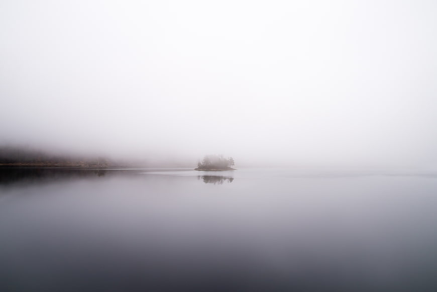 Misty Lake with Small Island and Foggy Horizon