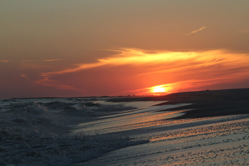 Dramatic orange sunset over ocean waves and sandy beach