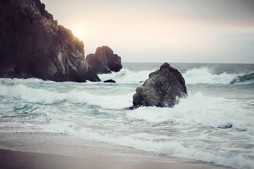 Dramatic Ocean Waves Crashing Against Rocky Cliffs at Sunset