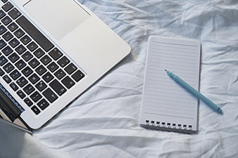 Laptop, Notebook, and Pen on White Bedding