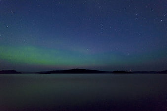 Aurora Borealis over calm lake with starry night sky