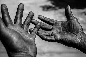 Close-up of dirty worker hands reaching out in black and white