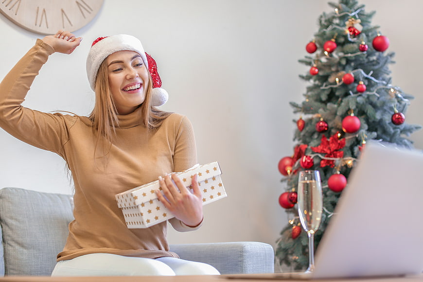 Happy woman celebrating Christmas with gift and laptop