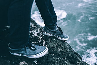 Man standing on rocky cliff edge overlooking ocean waves