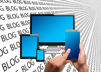 Hand Holding Smartphone With Tablet And Monitor Against Blog Text Background