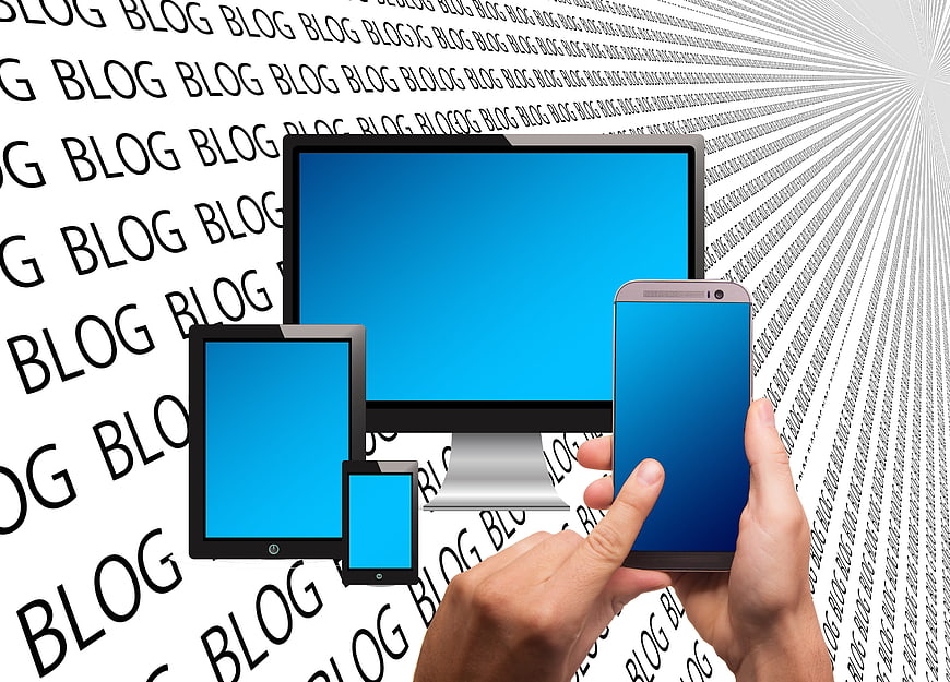 Hand Holding Smartphone With Tablet And Monitor Against Blog Text Background