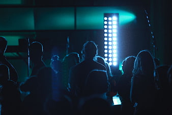 Silhouettes of crowd at concert with blue stage lights
