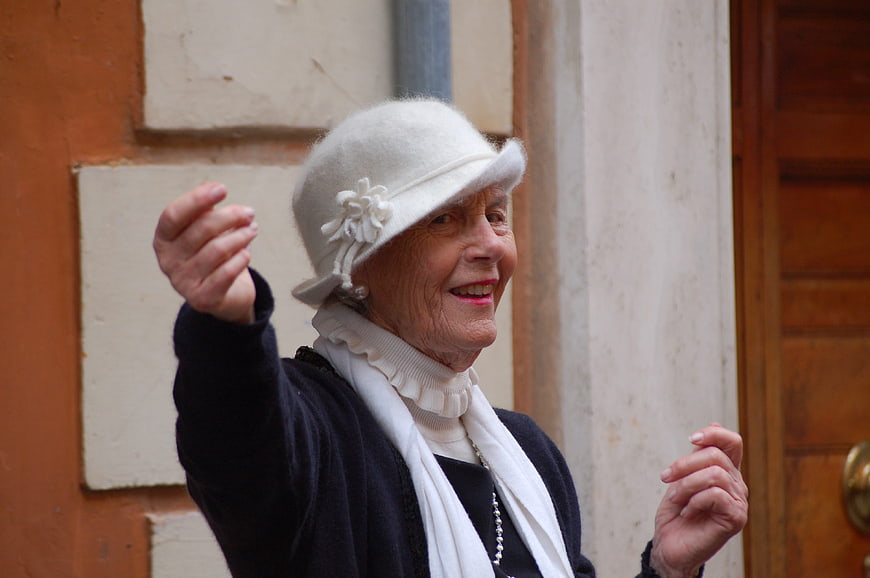 Joyful elderly woman in vintage hat gesturing outdoors