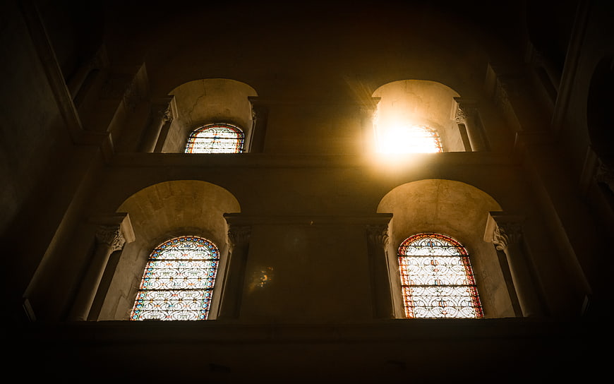 Sunlight streaming through arched stained glass church windows