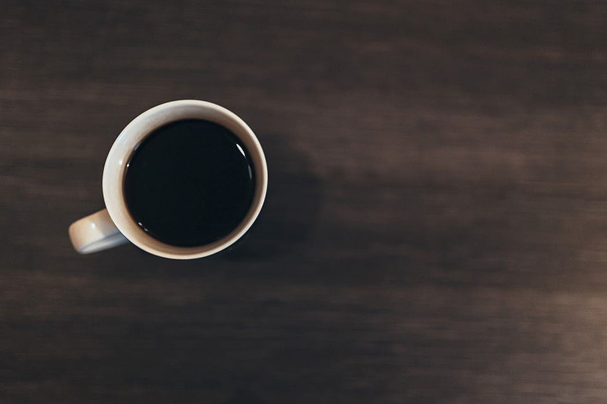 Top View of Black Coffee Cup on Dark Wood Table