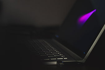 Dark laptop with purple light beam in low light