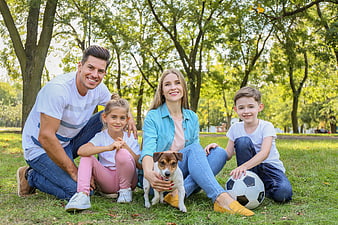 Happy family with dog and soccer ball in park