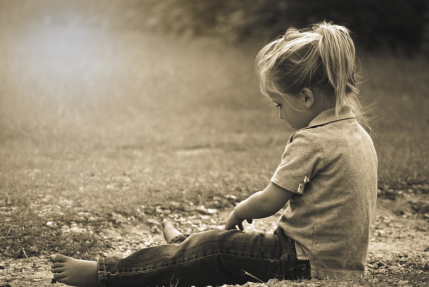 Toddler girl sitting on dirt path in sepia tone